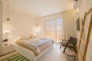 um quarto branco com uma cama e uma cadeira em Casa dos Pedros (Beach House) em São Roque