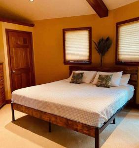 a bedroom with a large bed with two windows at A Magical Treehouse by the Sea! in Hilton Head Island