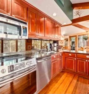 una cocina con armarios de madera y electrodomésticos de acero inoxidable en A Magical Treehouse by the Sea! en Hilton Head Island