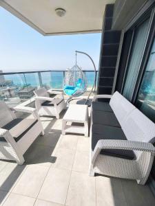 a balcony with chairs and a swing and the ocean at Panorama Apartment " City Garden " in Bat Yam