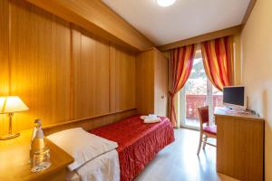 Dormitorio con cama, escritorio y TV en Hotel La Serenella, en Moena