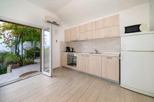 cocina con armarios de madera y nevera blanca en Apartments Juranic I, en Baška