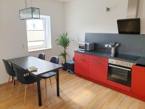 a kitchen with red cabinets and a table with a microwave at Ferienwohnung zur Flatterulme 1 in Weißwasser
