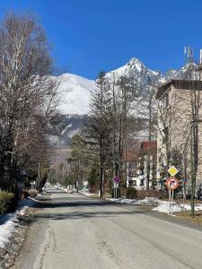 an empty street with a snow covered mountain in the background at Apartmán TATRAFUN in Tatranská Lomnica