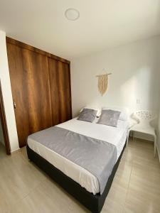 1 dormitorio con 1 cama grande y puerta de madera en Jardín de Primavera Apartamentos, en Jardín