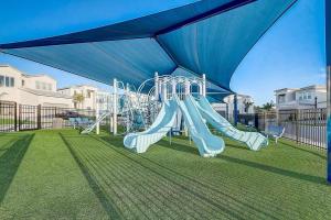 a playground with a blue canopy and a slide at luxury new 5 bedroom solterra resort close to disney in Davenport