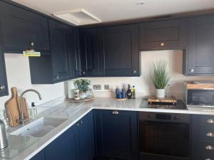 a kitchen with dark blue cabinets and a sink at Once upon a tide in Kent