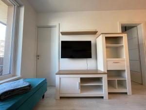 - un salon avec une télévision et une étagère dans l'établissement Modern and quiet apartment with air conditioning and free parking, à Košice