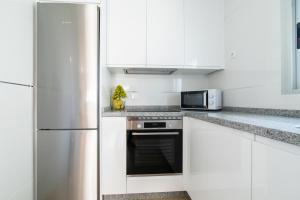 cocina con armarios blancos y nevera de acero inoxidable en Apartamentos Turísticos Casa Morocho, 
