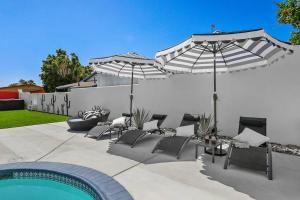 um pátio com guarda-sóis e cadeiras e uma piscina em L'Orangeraie: Mid Century Designer Desert Retreat em Palm Springs