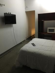 1 dormitorio con 1 cama y TV en la pared en CRK en San Pedro