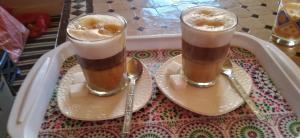 dos vasos de café sentados en una bandeja con cucharas en merzouga fatima Appart hotel &Camp, en Merzouga