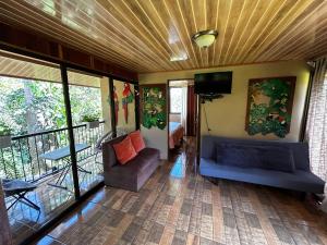 een kamer met een balkon, een bank en een televisie bij Cabaña en Alajuela en lugar tranquilo y con mucha naturaleza. in Tambor
