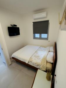 a small bedroom with a bed and a flat screen tv at Amazing 2Rooms Apt in Bat Yam - Step by the beach in Bat Yam