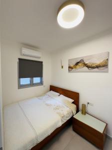ein weißes Schlafzimmer mit einem Bett und einem TV in der Unterkunft Amazing 2Rooms Apt in Bat Yam - Step by the beach in Bat Yam