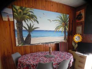a dining room with a table and a painting of a beach at shirley in Villars-les-Dombes