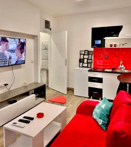 a living room with a red couch and a kitchen at Aurora in Kragujevac