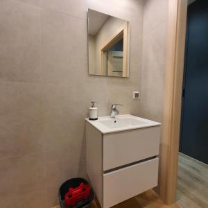 a bathroom with a white sink and a mirror at Apartament Holiday B 210 in Pobierowo
