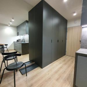 a kitchen with black cabinets and a table and chairs at Apartament Holiday B 210 in Pobierowo +11 photos