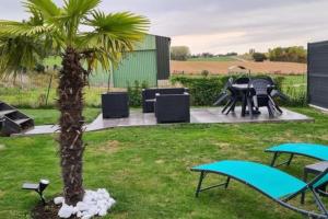 eine Palme im Garten mit Tischen und Stühlen in der Unterkunft maison nature spéciale JO 2024 in Savignies