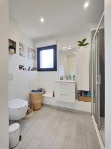 ein weißes Bad mit einem WC und einem Waschbecken in der Unterkunft maison nature spéciale JO 2024 in Savignies