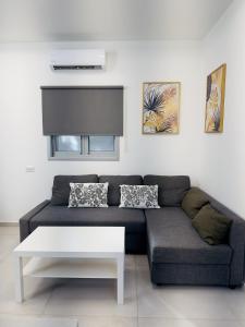 uma sala de estar com um sofá e uma mesa branca em Amazing 2Rooms Apt in Bat Yam - Step by the beach em Bat Yam