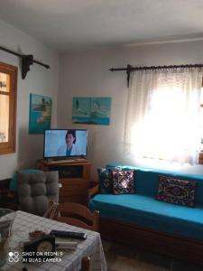 a living room with a blue couch and a tv at Persefoni's Traditional House in Promírion