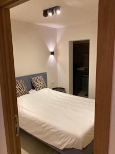 1 dormitorio con 1 cama grande con sábanas y almohadas blancas en Marco polo with free parking, en Knokke-Heist