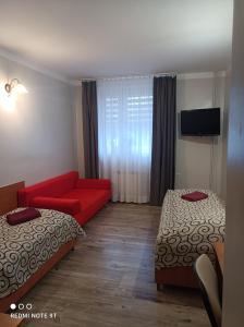 pokój hotelowy z 2 łóżkami i czerwoną kanapą w obiekcie Willa-Restauracja Victoria w Ostrowcu Świętokrzyskim