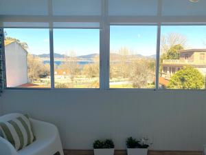 Zimmer mit vier Fenstern und einem Bett mit Pflanzen in der Unterkunft SAMIL PLAYA SUR in Vigo