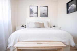 a white bedroom with a white bed and three pictures on the wall at SAMIL PLAYA SUR in Vigo