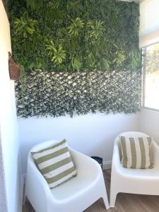 a room with a green wall with a white couch and a chair at SAMIL PLAYA SUR in Vigo
