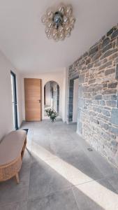 ein Wohnzimmer mit einer Steinmauer und einem Kronleuchter in der Unterkunft Ô Nuit Claire, superbe longère avec spa. in Dompierre-sur-Helpe