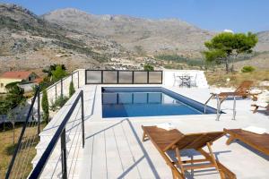 a house with a swimming pool with mountains in the background at Villa Branko 12km from Dubrovnik in Ravno