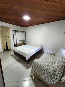 Un dormitorio con 2 camas y una silla. en Sítio Donana Sana en Macaé