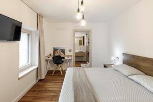 Habitación blanca con cama y escritorio en Casa21 en SantʼAntonio Tortal