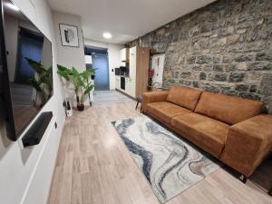 - un salon avec un canapé brun et un mur en pierre dans l'établissement Gîte Genius Loci, à Marche-en-Famenne