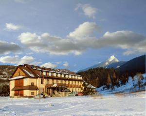 ein großes Gebäude im Schnee vor einem Berg in der Unterkunft Hotel Gold in Terchová