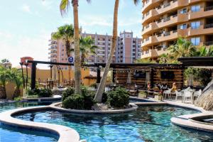 a swimming pool with palm trees and a hotel at Bella sirena 502-A in Puerto Peñasco