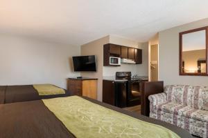 a hotel room with a bed and a couch and a television at Rodeway Inn & Suites Hwy 217 & 26 W in Portland