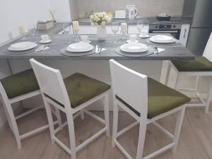 a kitchen table with two chairs and a white table with plates at Apartament Adora Alex in Arad
