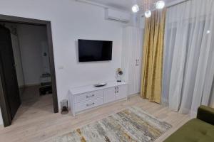 a white living room with a tv on a wall at Apartament Adora Alex in Arad