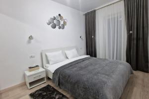 a white bedroom with a bed and a window at Apartament Adora Alex in Arad