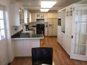una cocina con armarios blancos y una silla negra en 3118 Yellow House Main home en Pacific Grove