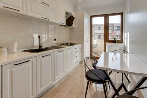 a kitchen with white cabinets and a table and chairs at D&C Apartament in Braşov