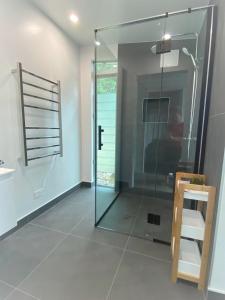 a glass shower stall in a bathroom with a sink at The Lakes - Kai Iwi Lakes Exclusive Retreat in Kaihu