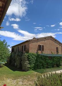 an old brick building with a green hedge at Villa Podere Cartaio Bio Estate Pool AirC in San Rocco a Pilli