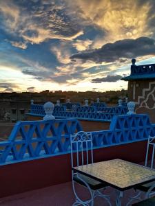 a table and chairs on a roof with a sunset at Riad Dades Birds in Boumalne Dades
