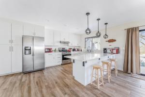 a white kitchen with white appliances and wooden floors at Close to JT Park & Town w/360 View The Green Adobe in Joshua Tree