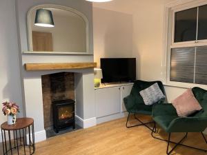 a living room with two chairs and a fireplace at May cottage in Stratford Upon Avon in Stratford-upon-Avon